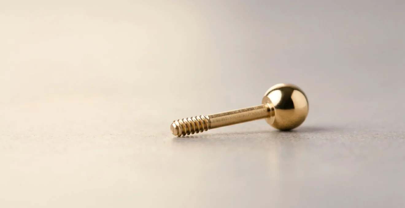 Gros plan sur un bijou de piercing en or massif présentant une finition miroir impeccable et une surface parfaitement lisse, symbolisant la sécurité et la biocompatibilité