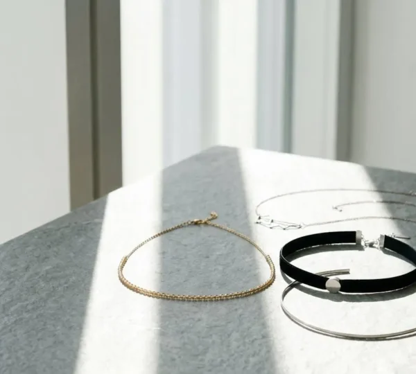 Composition minimaliste de chokers variés présentés sur une surface naturelle avec un jeu de verticales