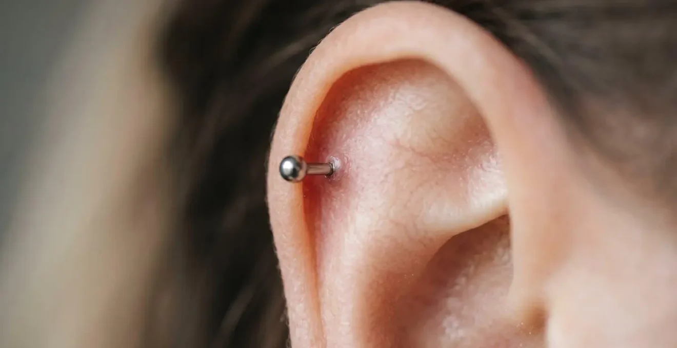 Gros plan artistique sur un cartilage d'oreille avec un piercing hélix en cours de cicatrisation, peau saine et bijou médical