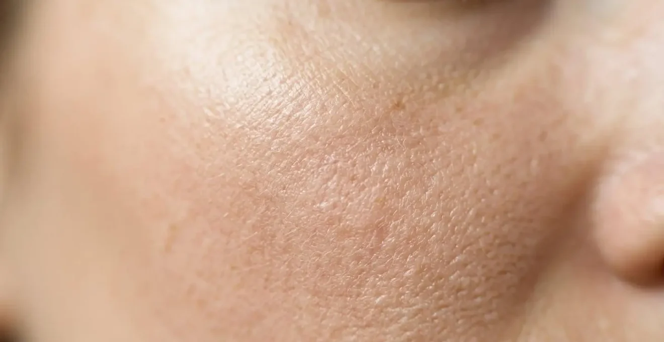 Gros plan sur une peau humaine saine avec texture naturelle visible montrant les pores dans une lumière douce et naturelle